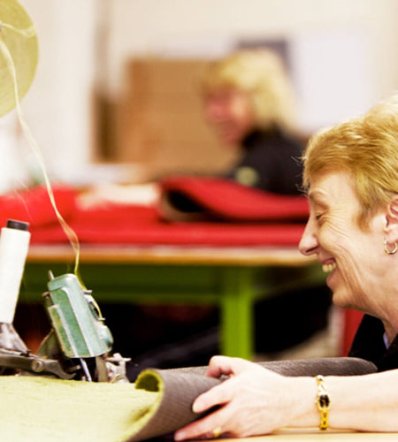 Factory worker at Phoenox Textiles sewing a doormat