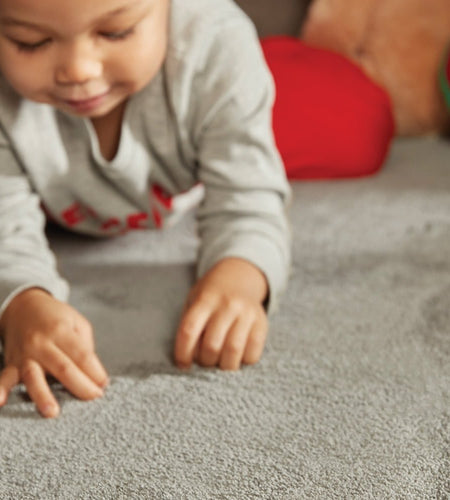 Young child crawling across a rug with noise reducing patent