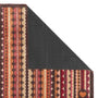 A close-up of a patterned doormat corner with one side folded back to show a dark textured backing, on a plain white background.
