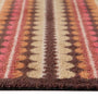 A close-up of a doormat with a Southwestern geometric pattern in brown, beige, pink, and orange, showing the textured pile and fringe edge.