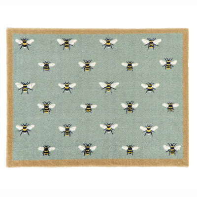 A rectangular area rug with a sage green background featuring a repeating pattern of bumblebees, finished with a natural coloured border.
