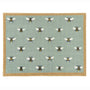 A rectangular area rug with a sage green background featuring a repeating pattern of bumblebees, finished with a natural coloured border.