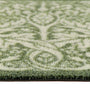 Close-up of a outdoor doromat  with a green and cream damask pattern, showing the pile height and the edge of the doormat. 