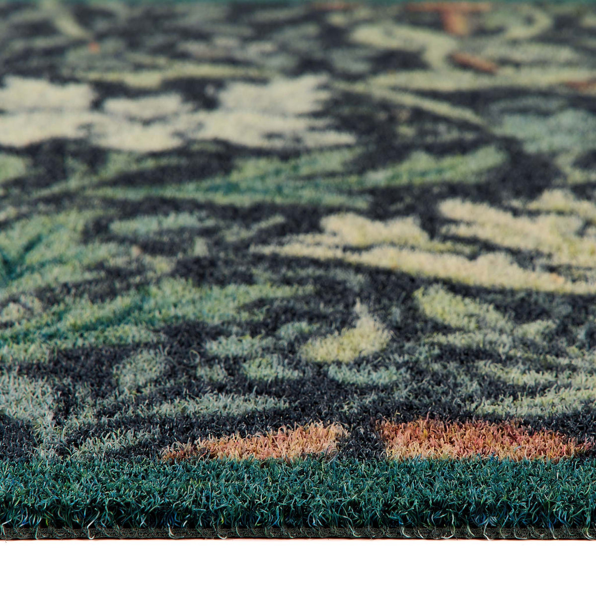 Close-up of a floral outdoor doormat with a dark green, black, and beige abstract floral pattern and a solid dark green shag border.