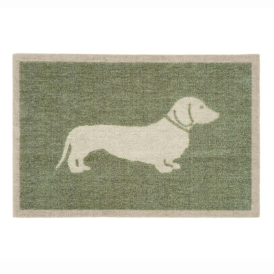 A rectangular doormat with a sage green textured background and a cream-colored silhouette of a dachshund dog, bordered by a cream edge.