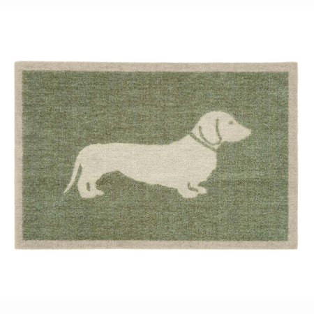 A rectangular doormat with a sage green textured background and a cream-colored silhouette of a dachshund dog, bordered by a cream edge.