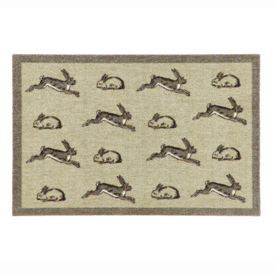 A rectangular doormat with a beige textured background, featuring a border and a repeating pattern of rabbits in gray and brown tones.