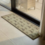 A rectangular indoor threshold runner with a repeating duck motif, shown on a tiled patio floor in front of a glass sliding door.