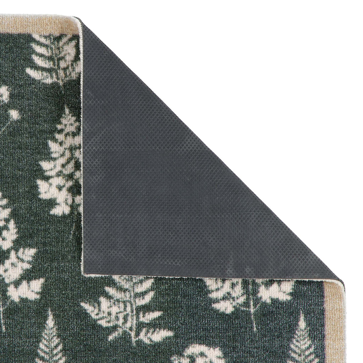Close-up of a folded rug corner showing a dark green  and off-white fern pattern on one side and a dark charcoal gray textured backing on the other, set against a plain white background.