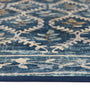 A close-up of a blue area rug with a distressed floral and leaf pattern in cream and muted brown tones.