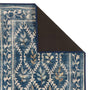 A close-up of a patterned area rug with a folded corner showing the dark backing, featuring a blue and cream floral vine design with subtle gold accents.