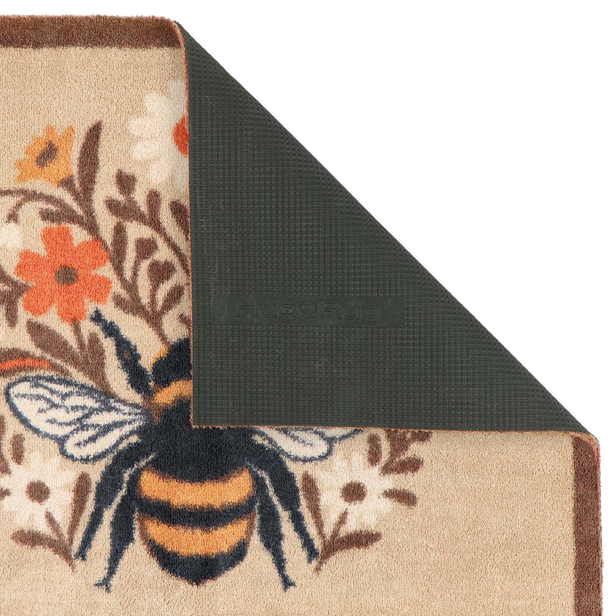 Close-up of a bee doormat with a beige background, featuring a large black and yellow bumblebee and orange flowers, with one corner folded over to show a dark green backing.