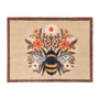 A rectangular doormat with a natural beige background, a dark brown border, and a central bumblebee motif surrounded by orange, white, and yellow flowers.