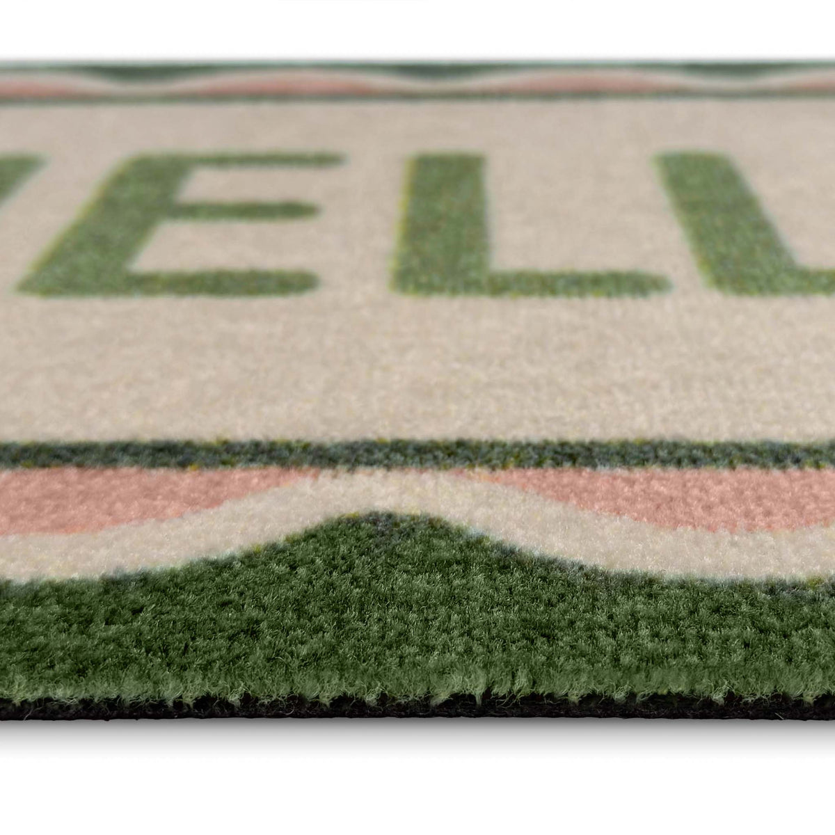 Close-up of a textured doormat with a cream background, green lettering, and a green and pink patterned border.