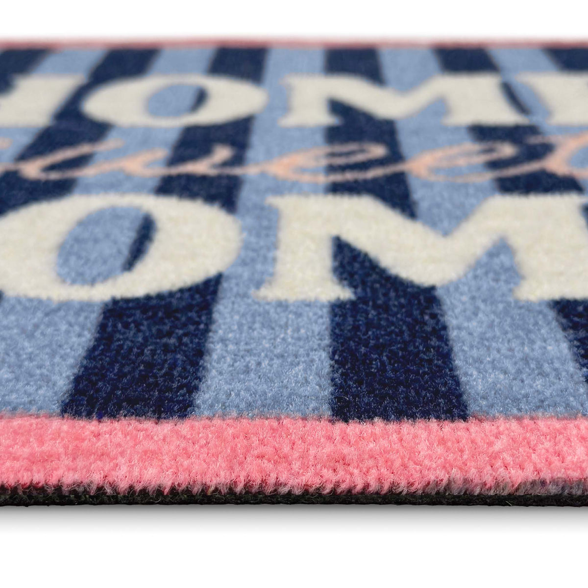 A close-up of a textured doormat featuring navy blue and light blue vertical stripes, cream lettering that reads 'HOME sweet HOME', and a pink border.