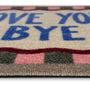Close-up of a doormat with the phrase 'LOVE YOU BYE' in blue letters on a cream background, with a multicolor striped border.