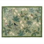 A rectangular area doormat with a natural woodland theme, featuring green oak leaves, beige leaves, and small birds in various colors, finished with a solid green border.