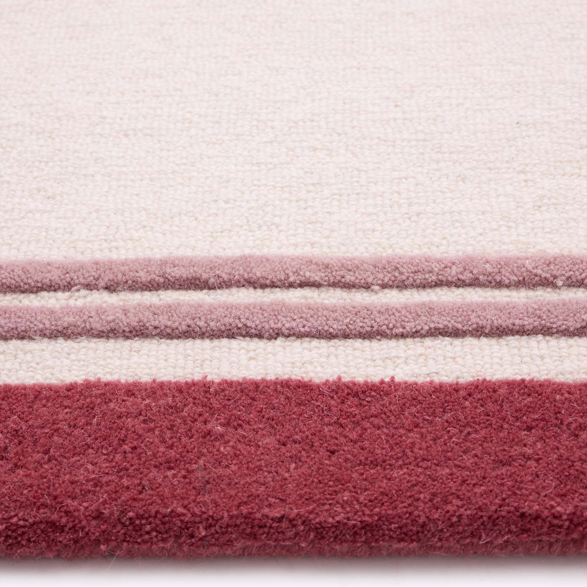 Orgins Piper Raspberry- 100% wool rug with a pink border.