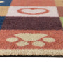 Close-up of a colorful textured runner with a cream paw print motif on a terracotta background and a white heart on an orange block.