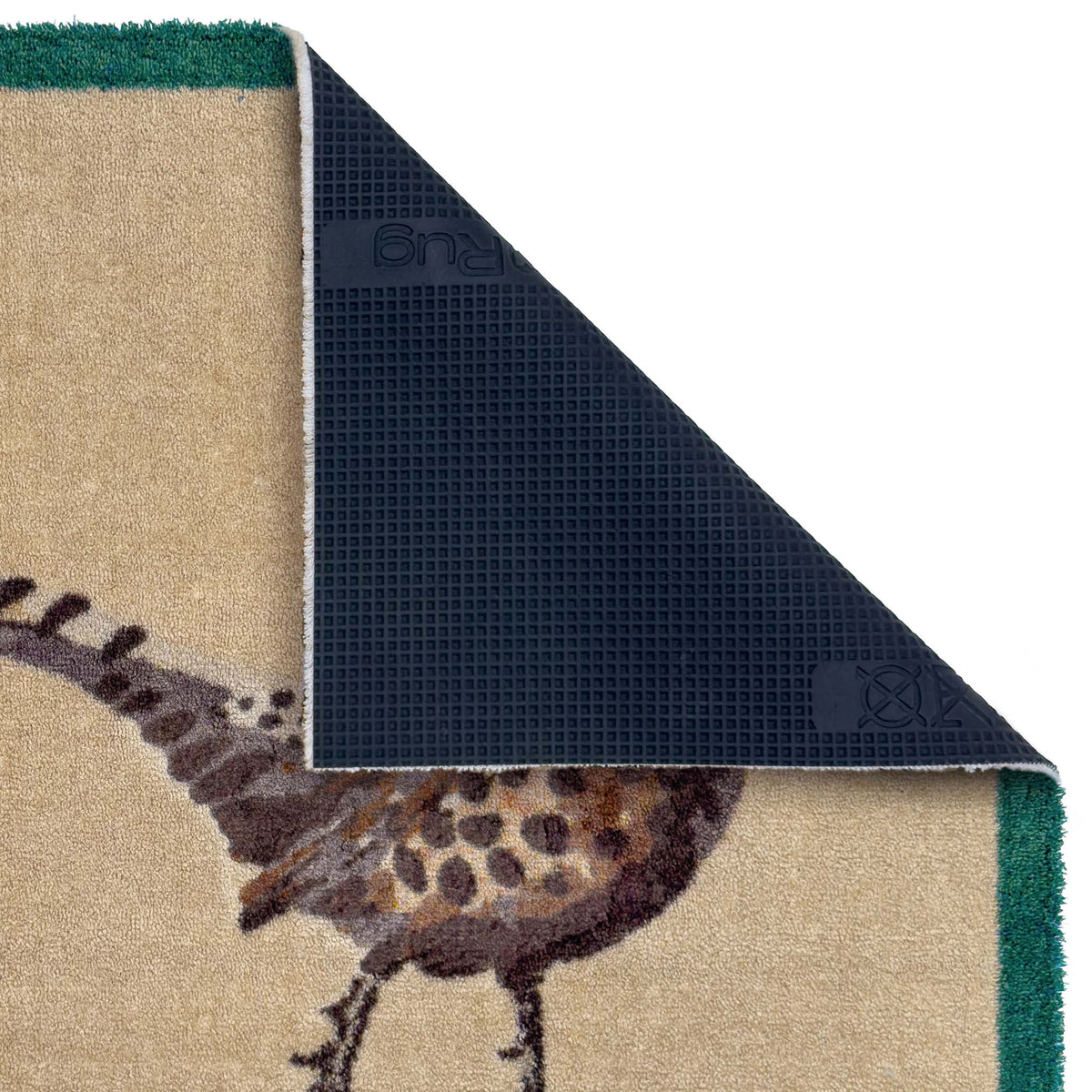 Close-up of the underside of a textured area doormat, showing a dark black backing with a grid texture and a small logo, alongside the beige rug surface with a brown and black bird motif and green border.