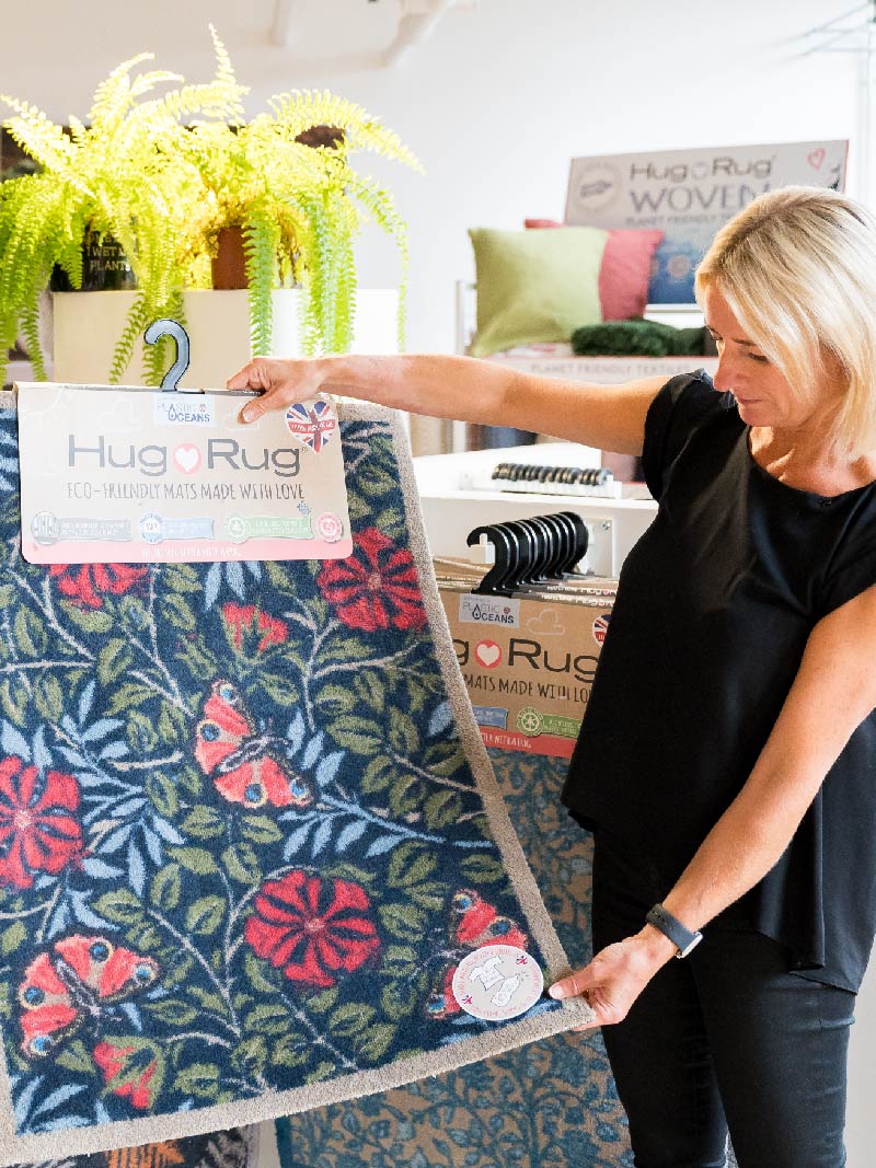 Woman holding a washable doormat from Hug Rug up for display