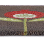Close-up of a textured doormat with a stylized flower design in red, white, and light green on a dark brown background.