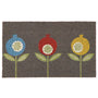 A rectangular grey coir doormat featuring a stylized pattern of three pomegranate-like flowers in blue, red, and yellow with green leaves and stems on a white background.