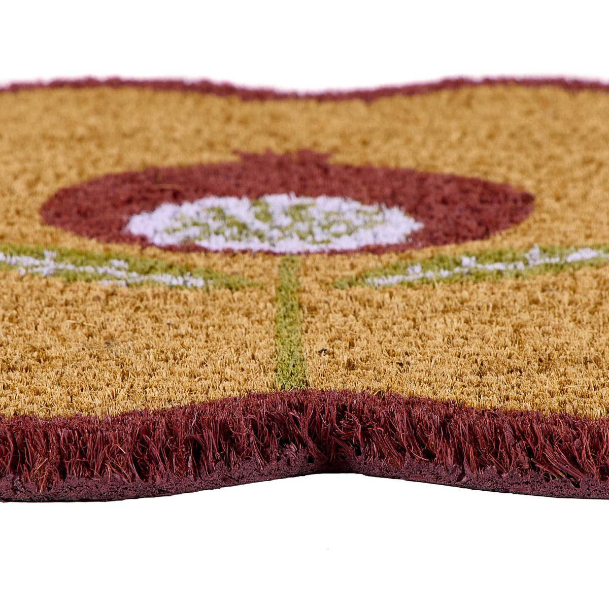 A close-up of a textured coir doormat with a stylized flower design in rust red, light green, and white, featuring a fringed edge on a white background.