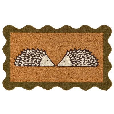 A rectangular coir doormat with a scalloped dark green border and a central design of two facing hedgehogs on a natural background, isolated on a white backdrop.