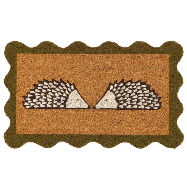 A rectangular coir doormat with a scalloped dark green border and a central design of two facing hedgehogs on a natural background, isolated on a white backdrop.