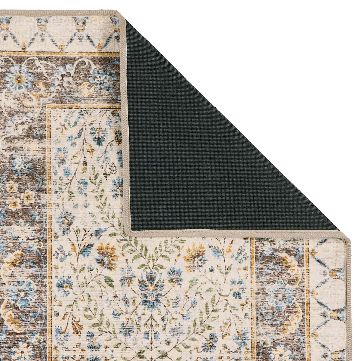 A close-up of a patterned area rug with one corner folded back to show the dark backing, on a plain white background.