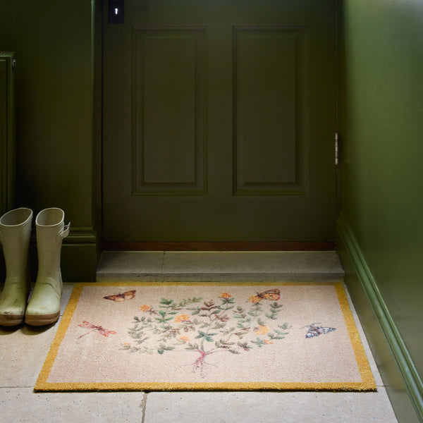 Sanderson By Highgrove x Hug Rug Thyme Walk Lichen & Gooseberry with a floral yellow design, styled by a green door. 