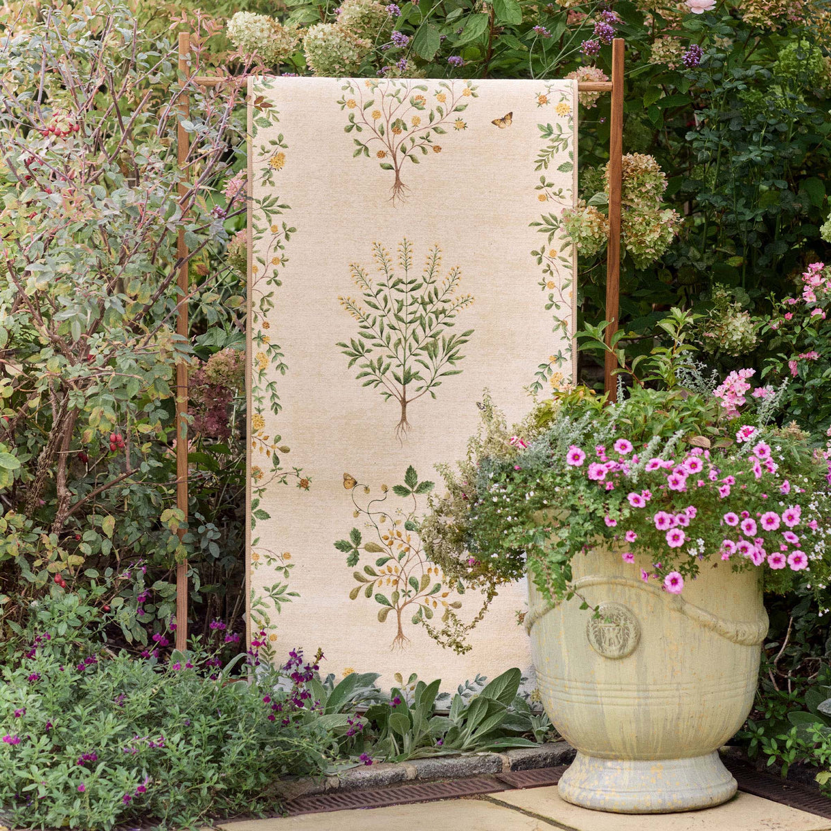 Sanderson By Highgrove x Hug Rug Eco-Washable Thyme Walk Lichen & Gooseberry with a nature inspired pattern, styled in a garden.