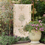 Sanderson By Highgrove x Hug Rug Eco-Washable Thyme Walk Lichen & Gooseberry with a nature inspired pattern, styled in a garden.
