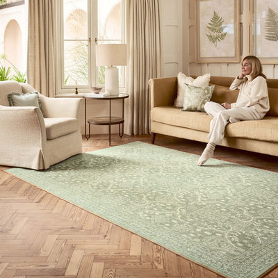 Sanderson By Highgrove x Hug Rug Eco-Washable Topiary View Thyme Rug in green with a traditional style pattern, styled in a living room. 