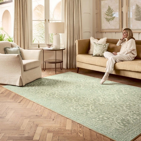 Sanderson By Highgrove x Hug Rug Eco-Washable Topiary View Thyme Rug in green with a traditional style pattern, styled in a living room. 