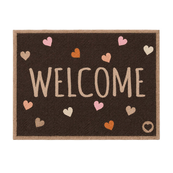 A rectangular brown doormat with a natural tan border, featuring the word 'WELCOME' in large beige letters and scattered pastel hearts in pink, orange, beige, and white.