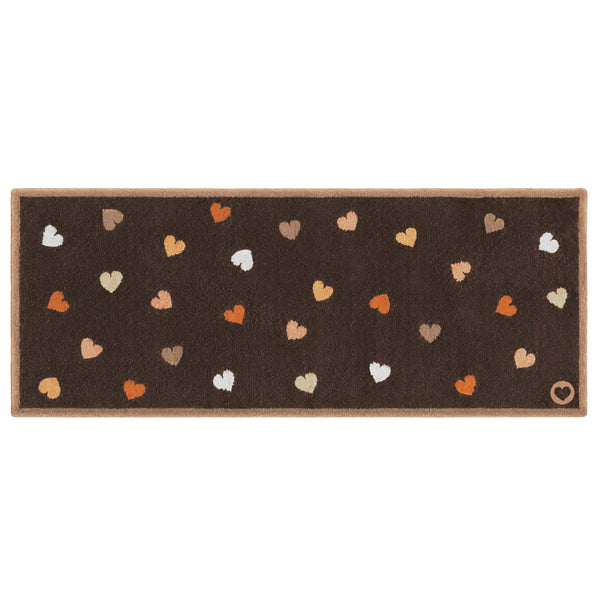 A rectangular brown mat with a border and scattered heart motifs in orange, beige, white, and brown, shown on a plain white background.