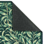 Close-up of a patterned outdoor doormat with a folded back dark gray underside, showing a green and beige leaf design on a white background.