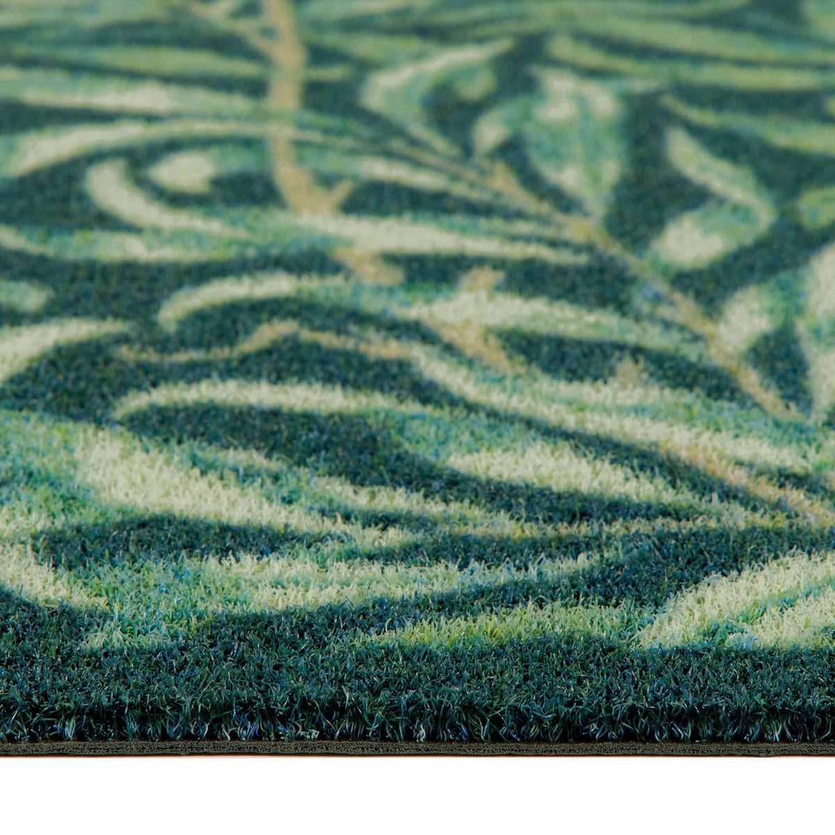 Close-up of a textured outdoor doormat with a leafy pattern in shades of green, teal, and cream.