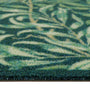 Close-up of a textured outdoor doormat with a leafy pattern in shades of green, teal, and cream.