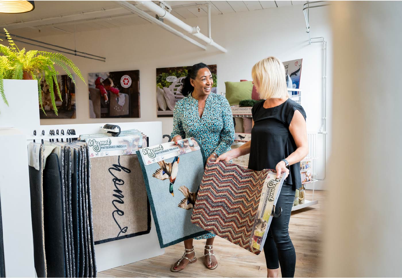 two women holding doormats in the phoenox textiles showroom