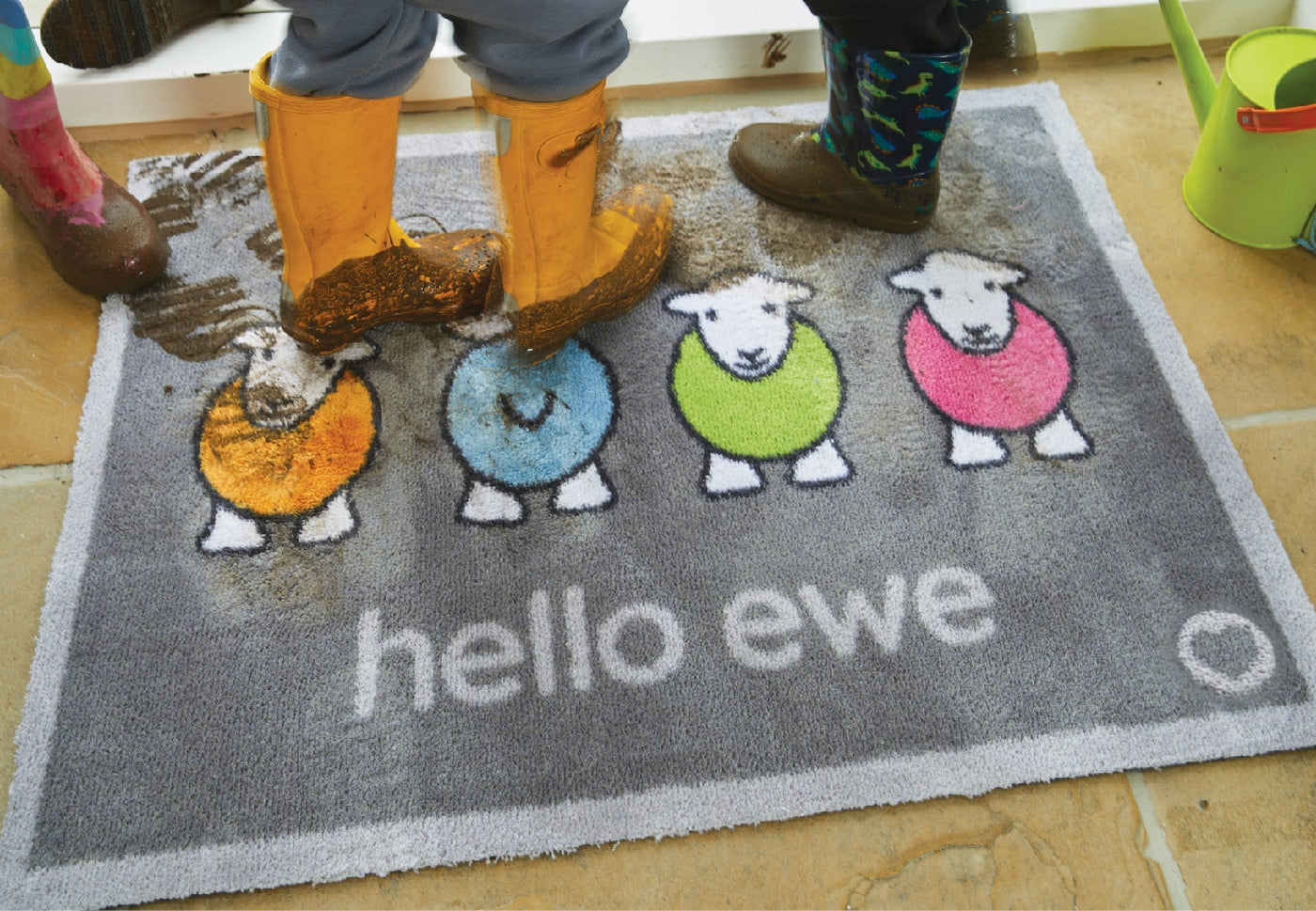 Muddy boots standing on a hello ewe herdy doormat at the front door