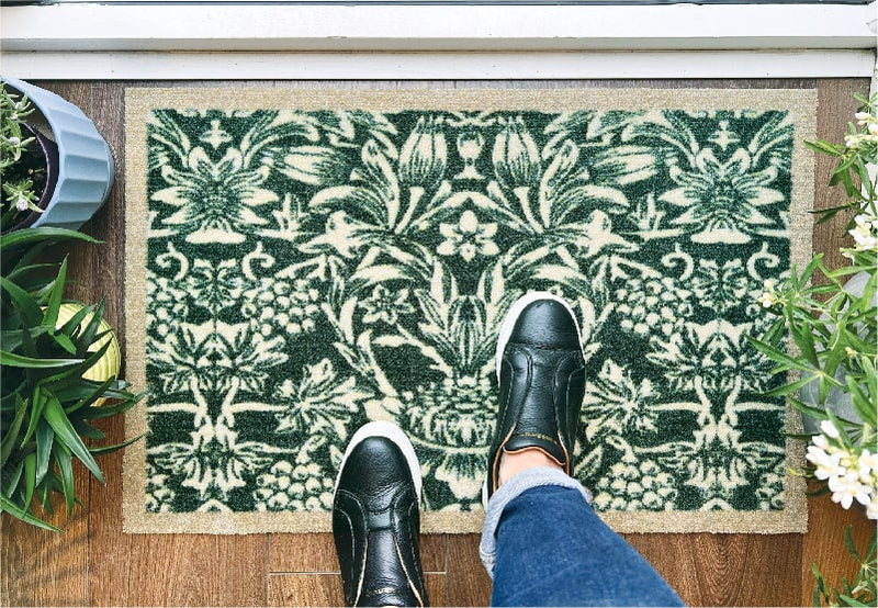 feet standing on a green floral front door doormat