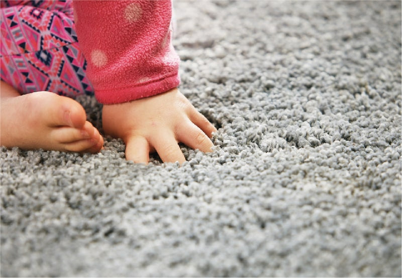 a child's hand plunging into a soft plush grey rug