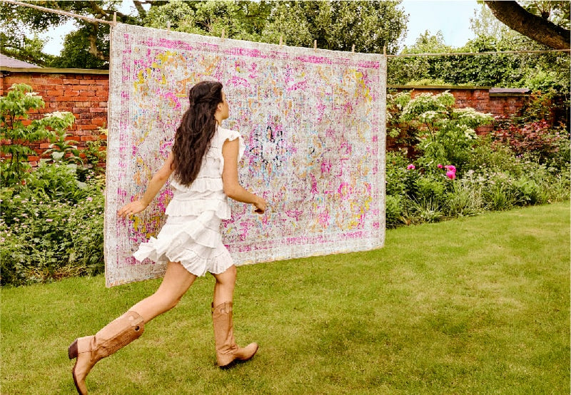 a woman running past a hug rug eco-washable rug on a washing line in the garden