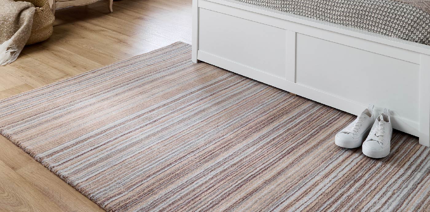 Biege and blue striped wool area rug on bedroom floor, manufactured by Phoenox Textiles