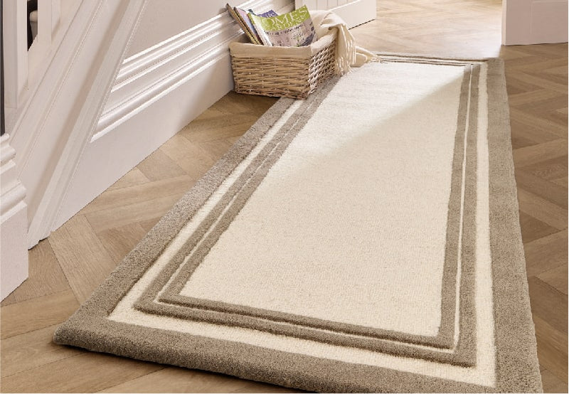 a white wool runner rug with brown borders on hallway floor