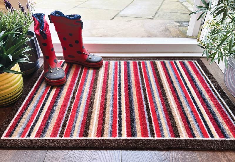 muddy wellies on a red striped doormat