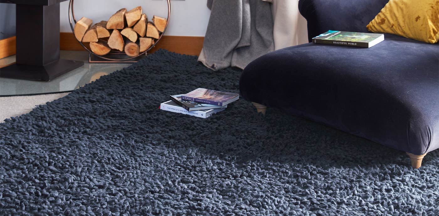 Navy blue shaggy area rug on living room floor, manufactured by Phoenox Textiles